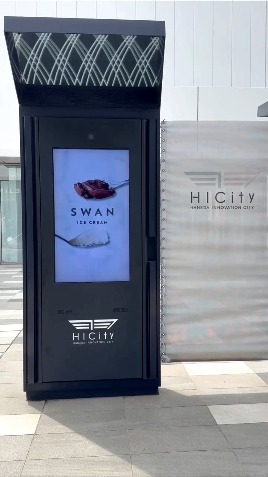 羽田イノベーションシティのサイネージに表示されたSWAN ICECREAMの広告。スプーンのアイスとSWANロゴが映る掲載風景